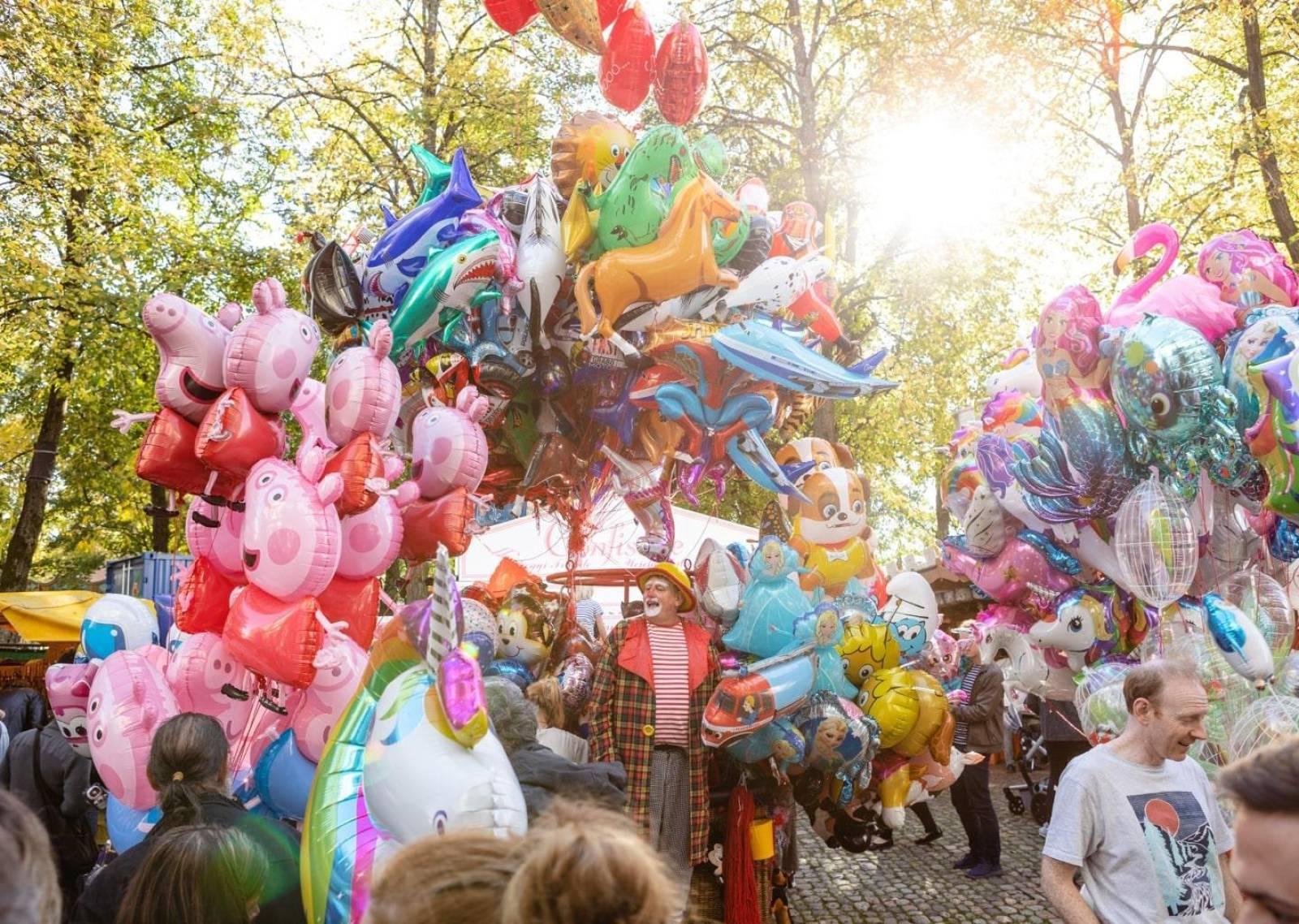 Fröhlicher Mann auf dem Petersplatz mit vielen Ballonen in allen Farben und Formen.