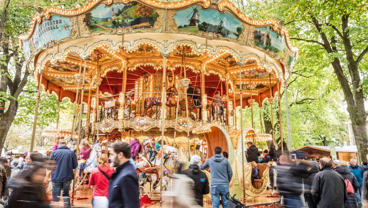 Lachende Kinder fahren auf dem wunderschön verzierten und beleuchteten Frankfurter-Pferdekarussell, unter den grossen Sommer-Linden auf dem Basler Petersplatz.