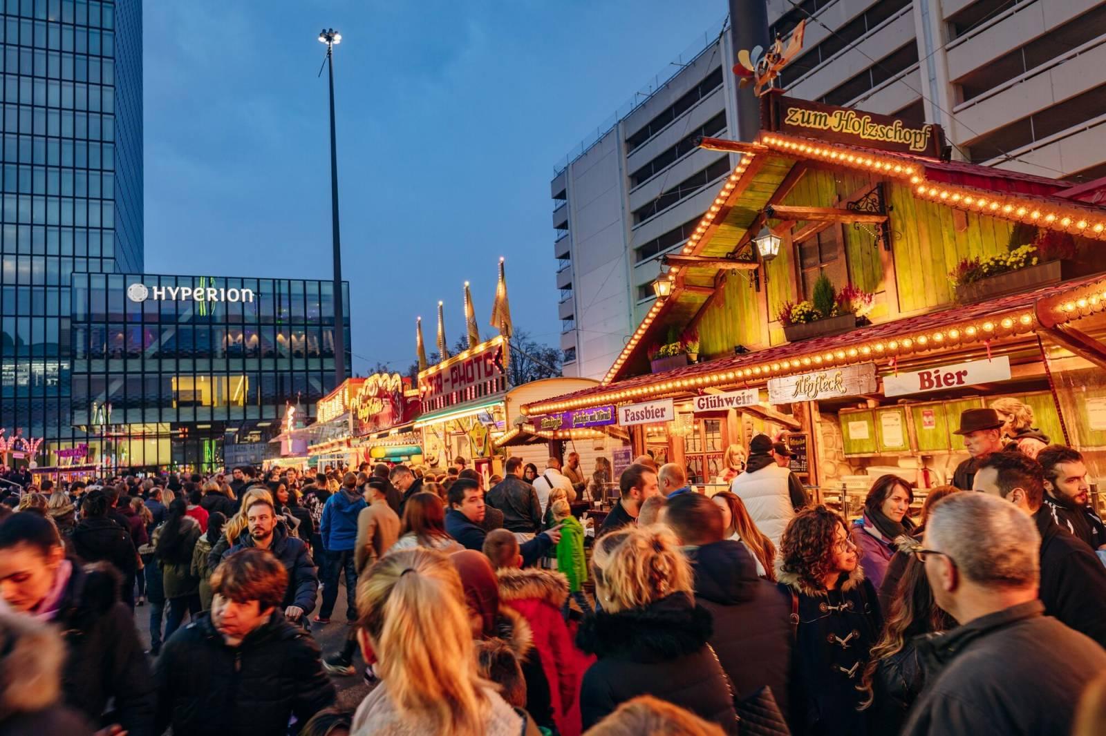 Abendstimmung mit zahlreichen Herbstmessebesucherinnen und -besuchern vor den hell beleuchteten Verpflegungsständen auf dem Basler Messeplatz.